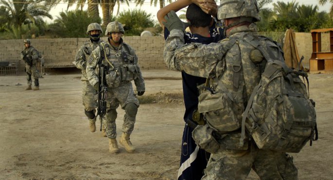 US Army soldiers restrain and search a detainee